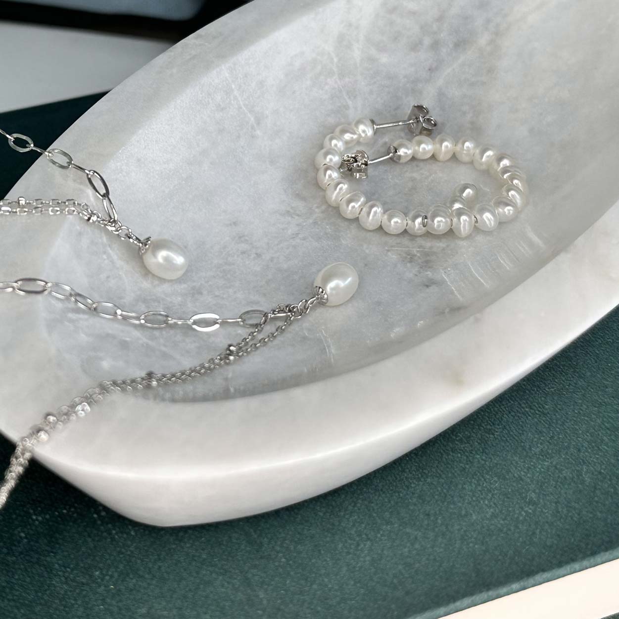 Pearl earrings and Charm necklaceon Marble tray
