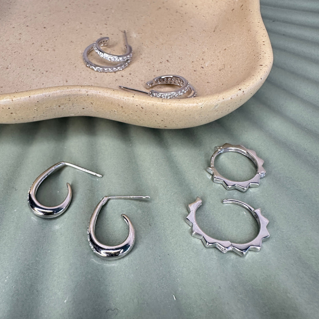 Silver hoop earrings on a textured surface