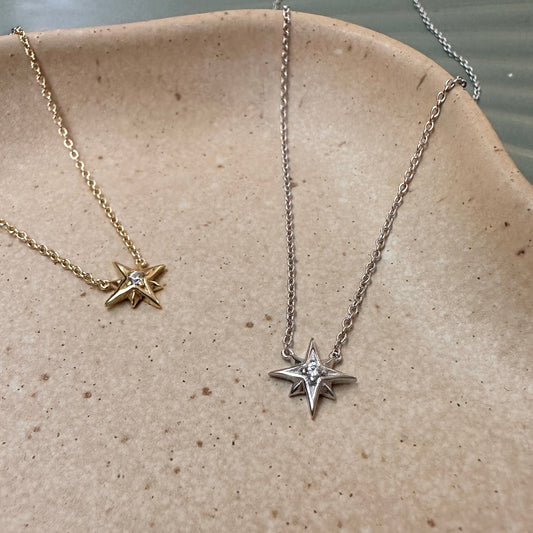 Two star-shaped pendant necklaces on a textured surface