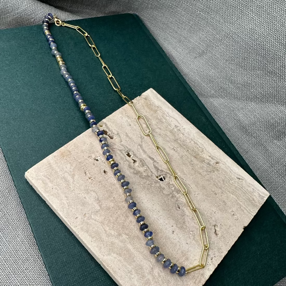 A paperclip link necklace with a combination of African Jade stones and gold nugget beads displayed on a flat surface.