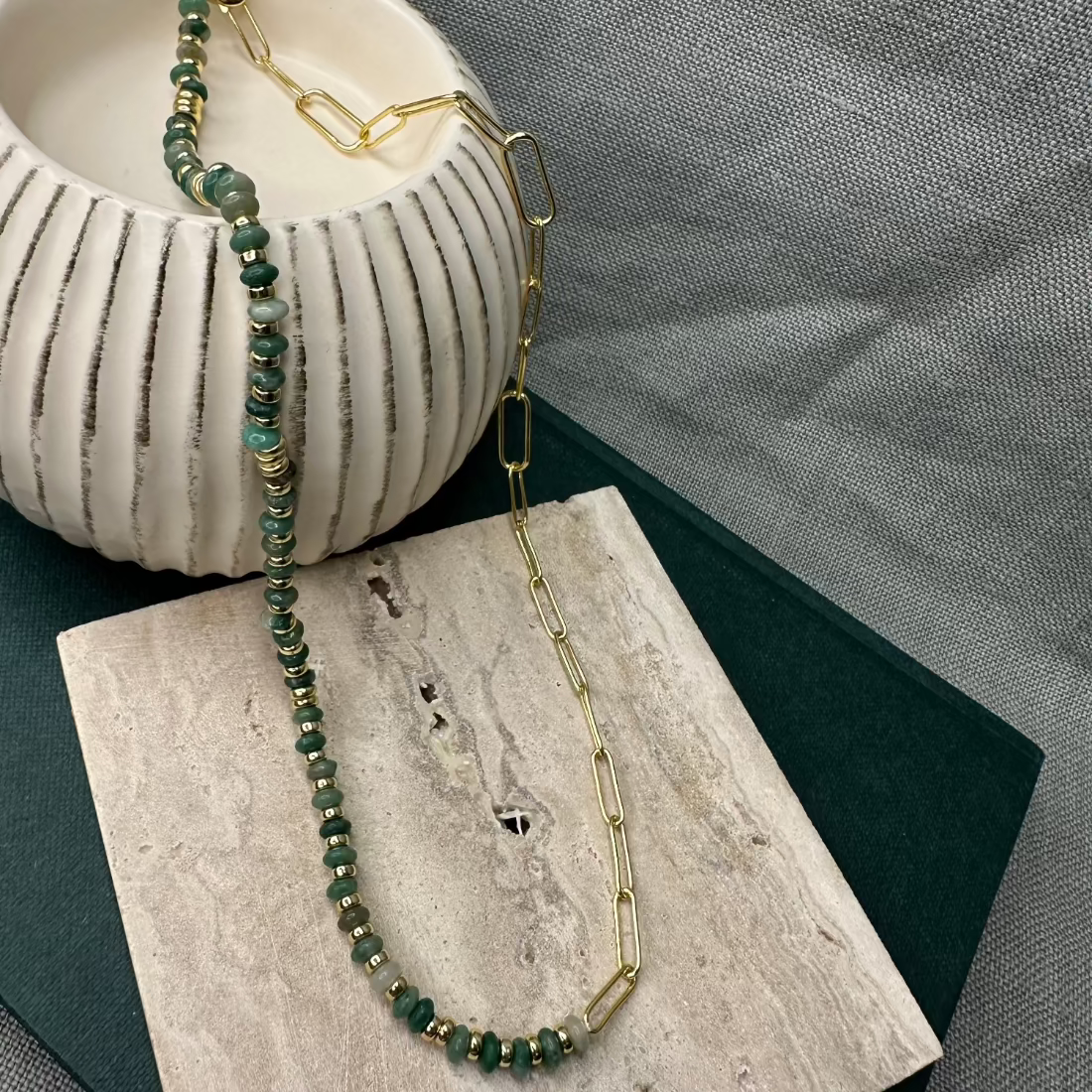 modern paperclip link neckjlace with green african jade stones laid on marble tile