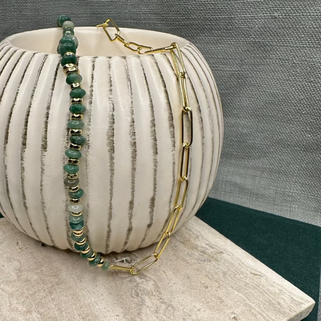 A paperclip link necklace with a combination of African Jade stones and gold nugget beads displayed on a flat surface.