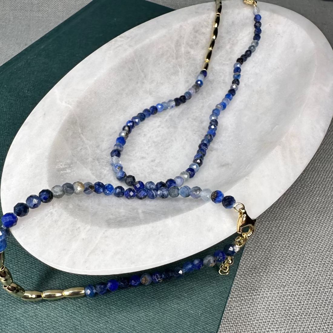 A gold nugget bracelet with blue sparkling cubic zirconia beads ideal for layering displayed on a white surface.