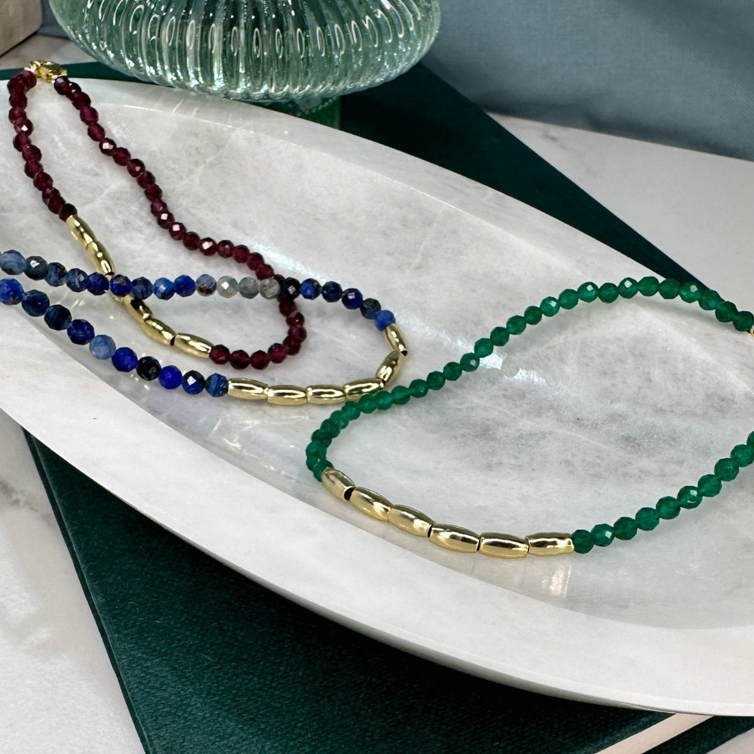 three gold nugget bracelets with green  red and blue sparkling cubic zirconia beads ideal for layering displayed on a marble tray