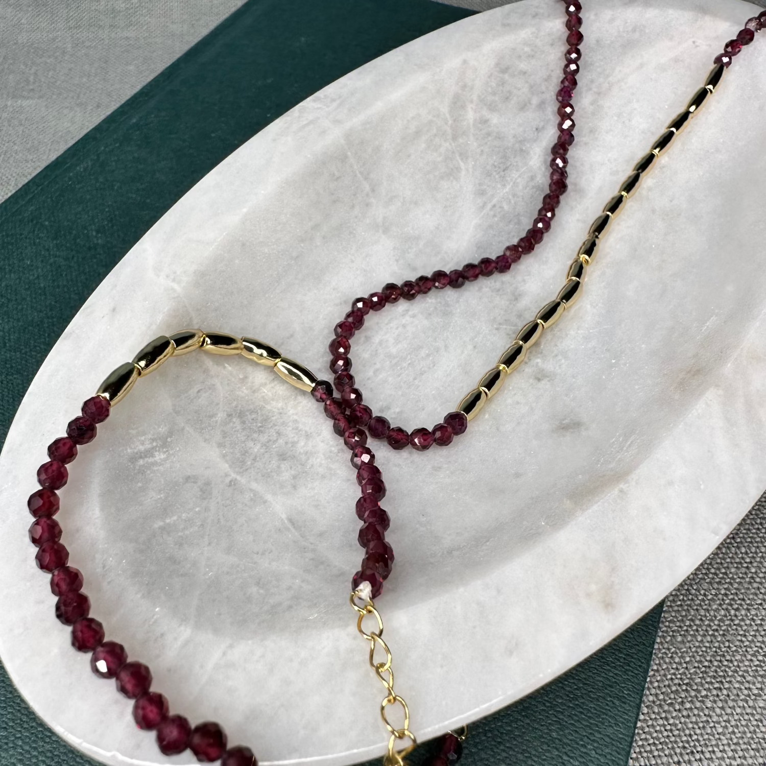 A gold nugget bracelet with ruby red sparkling cubic zirconia beads ideal for layering displayed on a white surface.