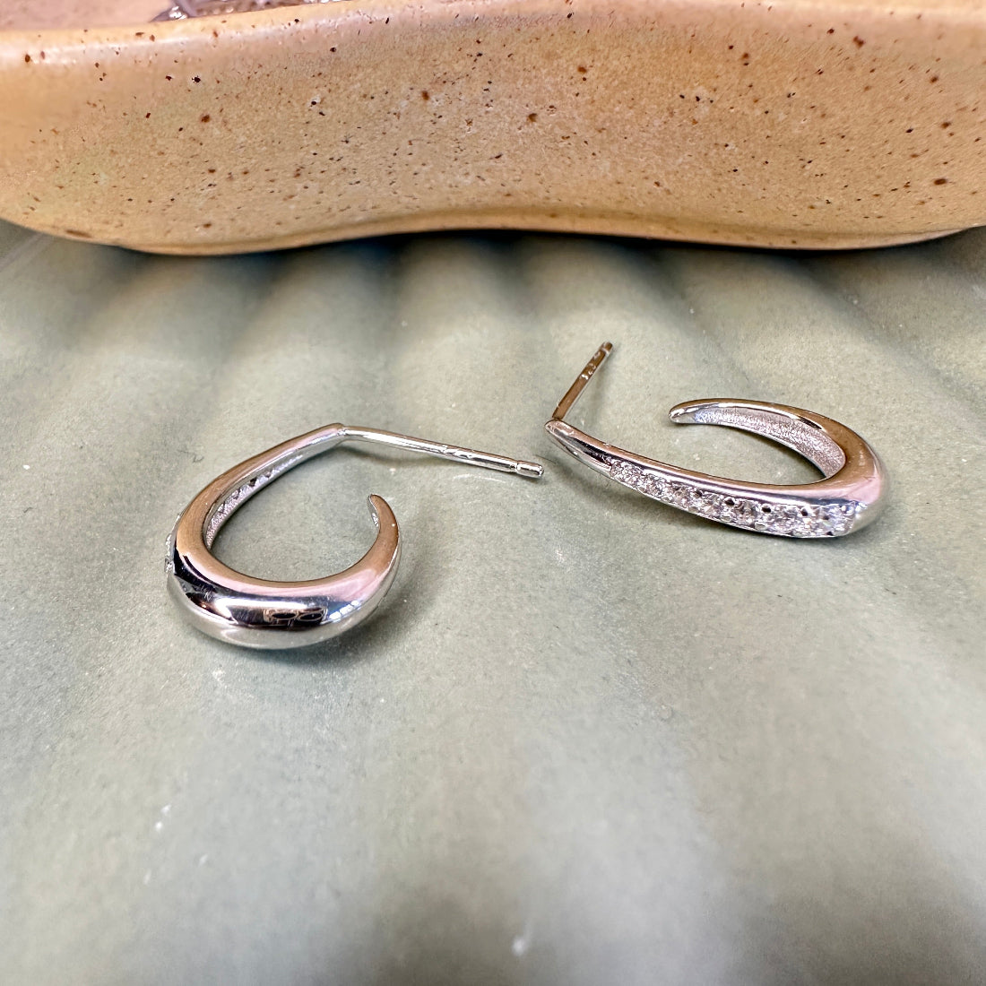 Silver hoop earrings on a textured surface