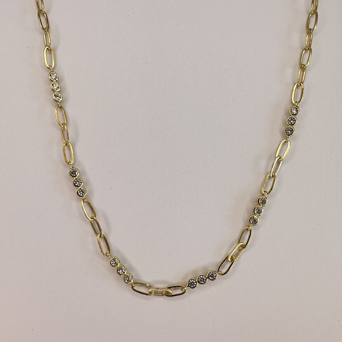 a close up image of a paperclip modern chain link necklace with triples of gemstones, laid on a white ground
