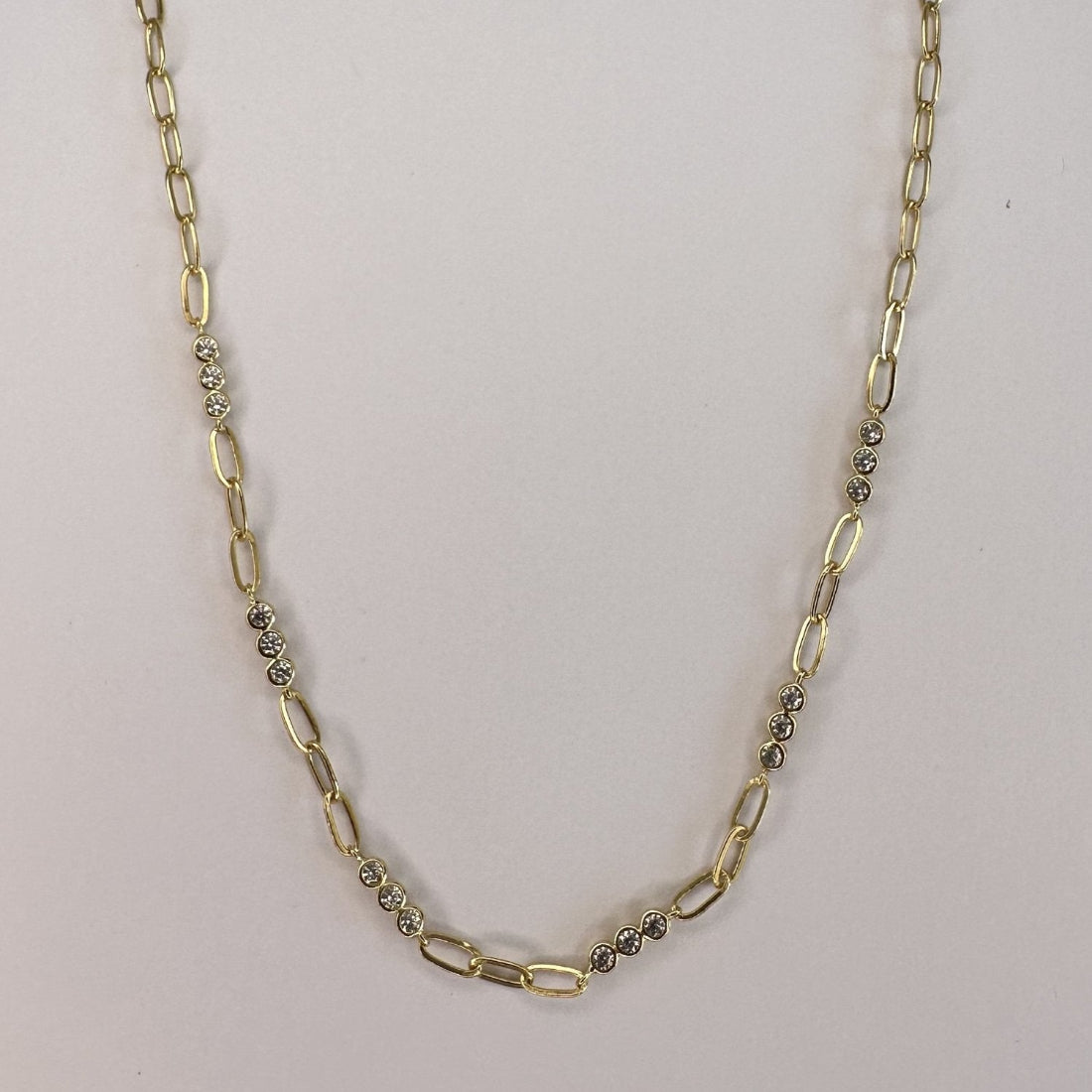 a close up image of a paperclip modern chain link necklace with triples of gemstones, laid on a white ground