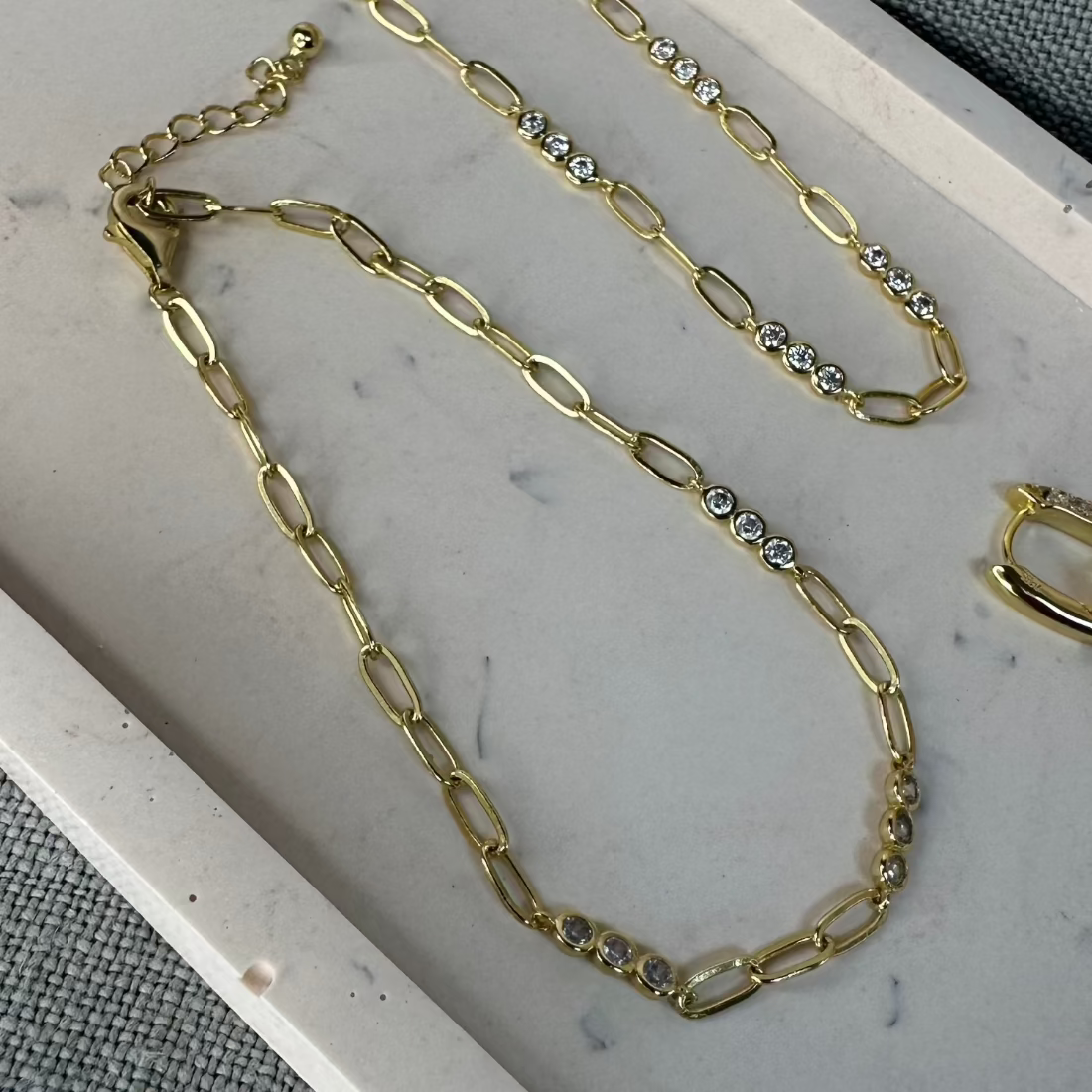 gold chain with cubic zirconia in triples formeda s a bralcet on a marble tray